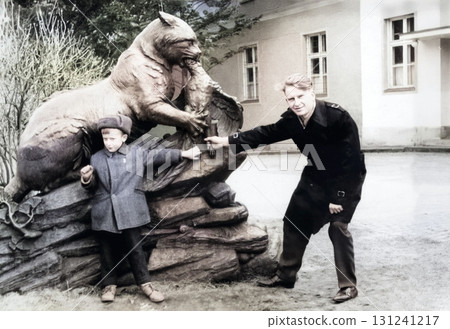 A vintage portrait of a military officer father with his young son. The father has placed his uniform cap on his son's head. Retro photo from 1973. 131241217