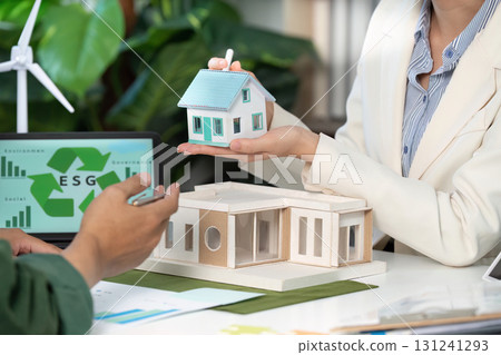 ESG focus. Professionals showcasing sustainable housing models in a collaborative meeting. ESG focus. Professionals showcasing sustainable housing models in a collaborative meeting. 131241293