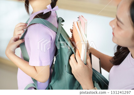 Back to School. A mother helps her daughter wear her backpack. 131241297
