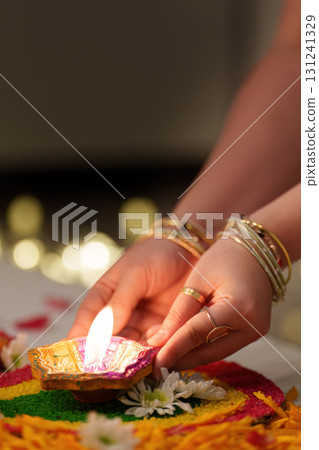Hands Placing Diwali Candle on Colorful Rangoli 131241329