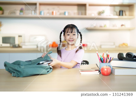 Back to School. Cheerful girl packing her backpack with school supplies. Back to School. Cheerful girl packing her backpack with school supplies. 131241369
