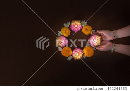 Hands Holding Diwali Candles Surrounded by Flowers 131241383