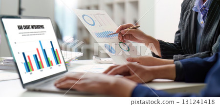 Strategic Review. Business team evaluating financial performance with charts and laptop. Strategic Review. Business team evaluating financial performance with charts and laptop. 131241418
