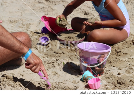 Father and daughter building sandcastles on beach with toys 131242050