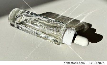 Glass cosmetic dropper bottle with serum on white background with sunlight and shadow minimalist skincare product mockup Glass cosmetic dropper bottle with serum on white background with sunlight and shadow minimalist skincare product mockup 131242074