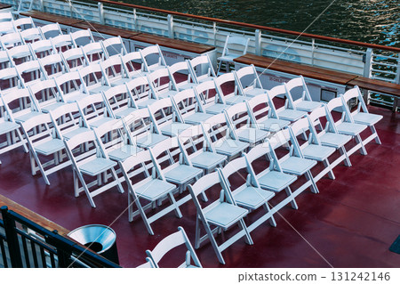 Rows of white chairs arranged on a boat deck, ready for an event. 131242146
