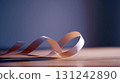 Pink satin ribbon lying on wooden surface with soft light and shadows, minimal composition with elegant and romantic mood 131242890