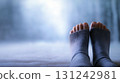 Bare toes peeking from cozy wool socks resting on cold snowy surface with blue winter background 131242981