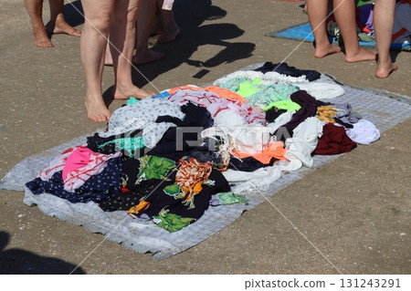 Beachgoers are browsing colorful pareos at an outdoor market on a sunny summer day 131243291