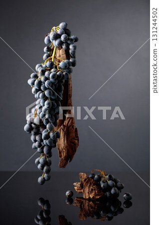 Blue grapes and weathered snags on a black reflective background. Blue grapes and weathered snags on a black reflective background. 131244502