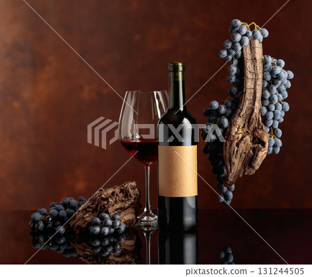 Red wine with a weathered snag and blue grapes on a brown background. 131244505