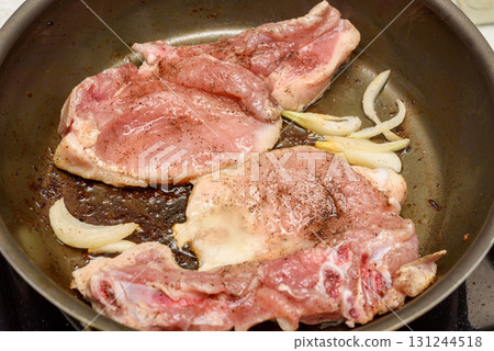 Marinated meat is fried with onions and vegetable oil in a frying pan. 131244518