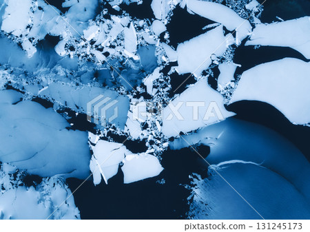 Aerial drone view of cracked ice floes on frozen lake surface 131245173