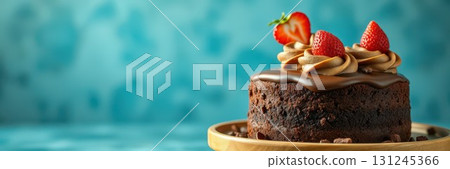 Chocolate cake topped with fresh strawberries and creamy frosting on a wooden platter against a blue backdrop 131245366