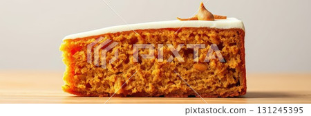 Deliciously moist pumpkin cake topped with creamy frosting and a hint of spice on a wooden table setting 131245395