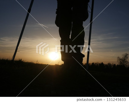 Person is standing in a field with a sunset in the background 131245633