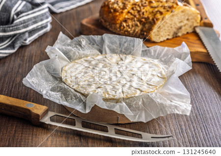 Camembert cheese on wrapping paper. French cheese with mold on the surface. Camembert cheese on wrapping paper. French cheese with mold on the surface. 131245640