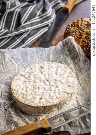 Camembert cheese on wrapping paper. French cheese with mold on the surface. Camembert cheese on wrapping paper. French cheese with mold on the surface. 131245642