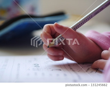 Child is writing with a pencil on a piece of paper Child is writing with a pencil on a piece of paper 131245662