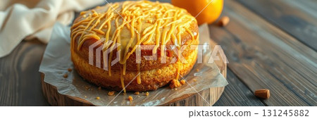 Delicious orange cake with caramel drizzle set on a rustic wooden table surrounded by fresh oranges and nuts 131245882