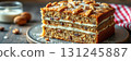 Delicious layered cake topped with nuts and icing served on a rustic wooden table 131245887