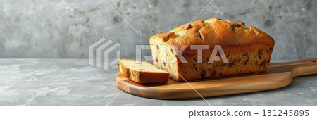 Freshly baked loaf of bread on a wooden cutting board surrounded by a rustic kitchen setting 131245895