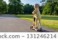 Scooter child. Girl riding scooter toddler. Yellow outdoor activity park road. 131246214