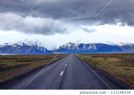 A straight road leads toward snow capped mountains 131246530