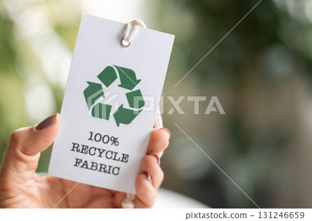Hand holding recycle fabric tag promoting sustainable eco-friendly textile production 131246659