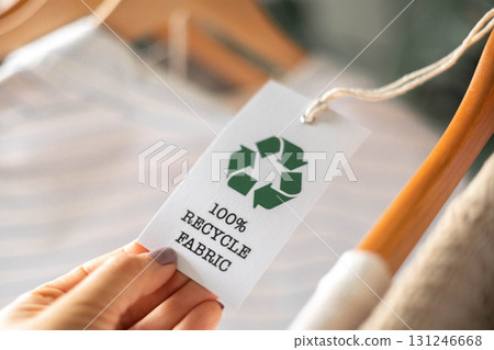 Eco clothing tag with recycle fabric symbol on clothes hanger for sustainable fashion 131246668