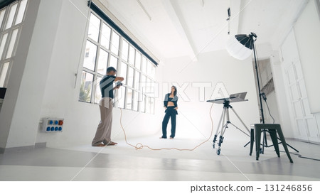 Photographer taking pictures of model posing in photo studio Photographer taking pictures of model posing in photo studio 131246856