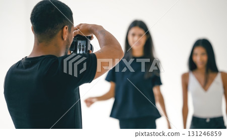 Photographer taking photos of two fashion models in studio Photographer taking photos of two fashion models in studio 131246859