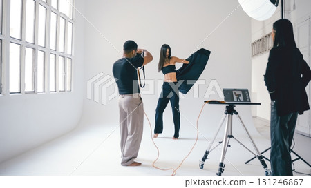 Photographer taking pictures of fashion model posing in studio 131246867
