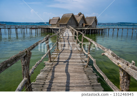 an old wooden bridge leading to a wooden bungalow on stilts across the lagoon an old wooden bridge leading to a wooden bungalow on stilts across the lagoon 131246945