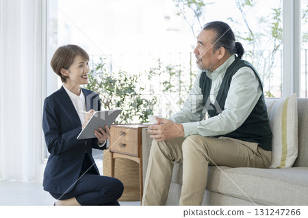Female facility staff with a tablet talking to a senior man Female facility staff with a tablet talking to a senior man 131247266
