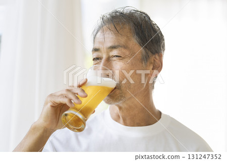 一名 60 多歲的男子正在喝啤酒 一名 60 多歲的男子正在喝啤酒 131247352