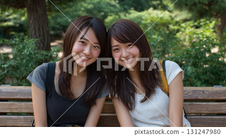 Two friendly girls sitting on a bench 131247980