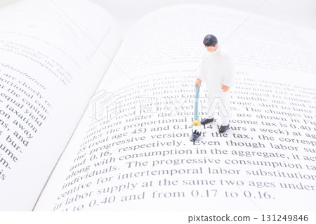 Miniature Man On Open Book: Economics And Tax Imagery Miniature Man On Open Book: Economics And Tax Imagery 131249846