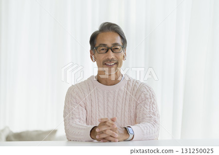 一名 60 多歲的男子戴著耳機對著鏡頭說話 一名 60 多歲的男子戴著耳機對著鏡頭說話 131250025