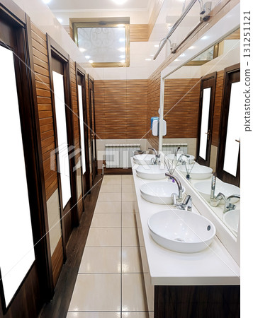 interior of a public restroom with wooden doors, ceramic sinks and faucets 131251121