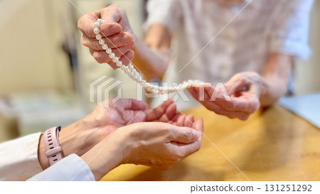 女人的手給一位老婦人一條珍珠項鍊 女人的手給一位老婦人一條珍珠項鍊 131251292