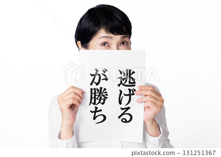 A senior woman grinning while hiding behind a piece of paper that says "Run away to win" A senior woman grinning while hiding behind a piece of paper that says "Run away to win" 131251367