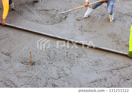 Construction workers are leveling freshly poured concrete using long metal tool to leveling concrete 131251522