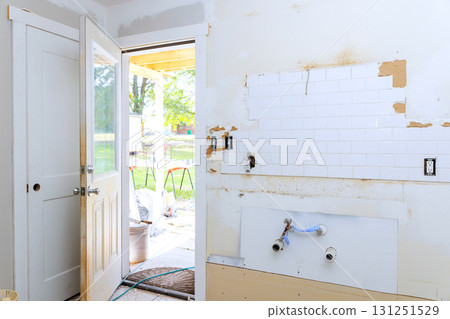 Bare walls exposed plumbing, room renovation door opens to sunny outdoor space. 131251529