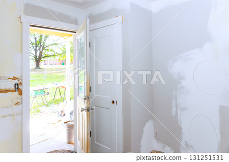 Room in middle of renovation with an open door revealing sunny outdoor space tools Room in middle of renovation with an open door revealing sunny outdoor space tools 131251531