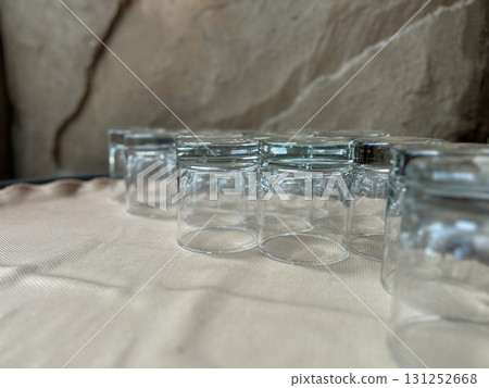 A row of small empty clear glass jars arranged on a textured cloth surface 131252668