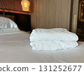 Neatly folded white towels arranged on a clean hotel bedroom bed 131252677