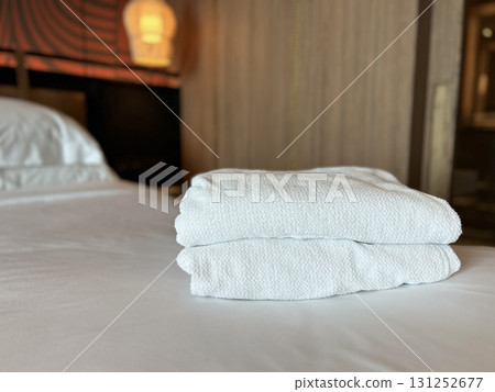 Neatly folded white towels arranged on a clean hotel bedroom bed Neatly folded white towels arranged on a clean hotel bedroom bed 131252677