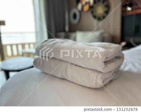 Neatly folded white towels stacked on a soft bed in a hotel room Neatly folded white towels stacked on a soft bed in a hotel room 131252678