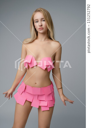 Blonde woman posing creatively in studio setting with sticky notes as clothing 131252792